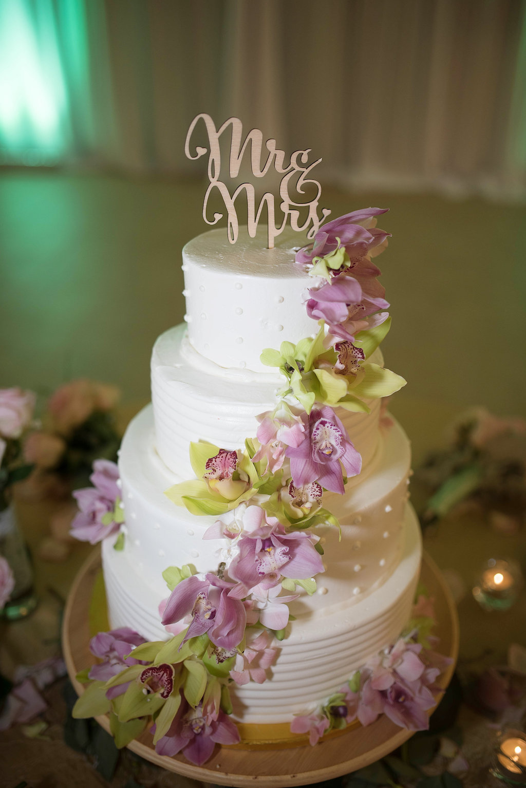 Four Tiered Round White Wedding Cake with Pink Florals and Greenery and Stylish Mr and Mrs Gold Cake Topper on Natural Wood Cake Stand | Tampa Bay Wedding