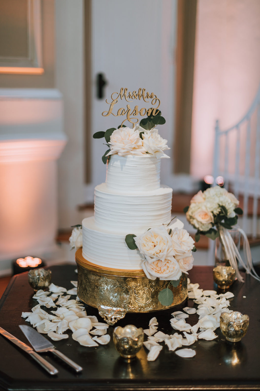 Three Tiered Round White Wedding Cake with Blush Pink Florals and Greenery, with Stylish Gold Cake Topper and Gold Cake Stand