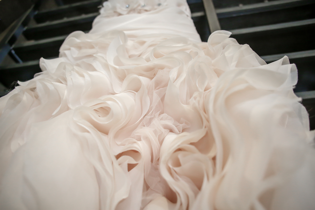 Detail Photo of Blush Ruffled Skirt of Wedding Dress on Hanger
