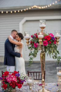 Luxurious Outdoor Tampa Bay Wedding Reception First Dance Portrait, with Navy Blue Linens, and Tall Gold Candelabra Centerpieces with Red, Magenta, and Purple Florals with Greenery | Tampa Wedding Photographer Caroline & Evan Photography | Northside Florist