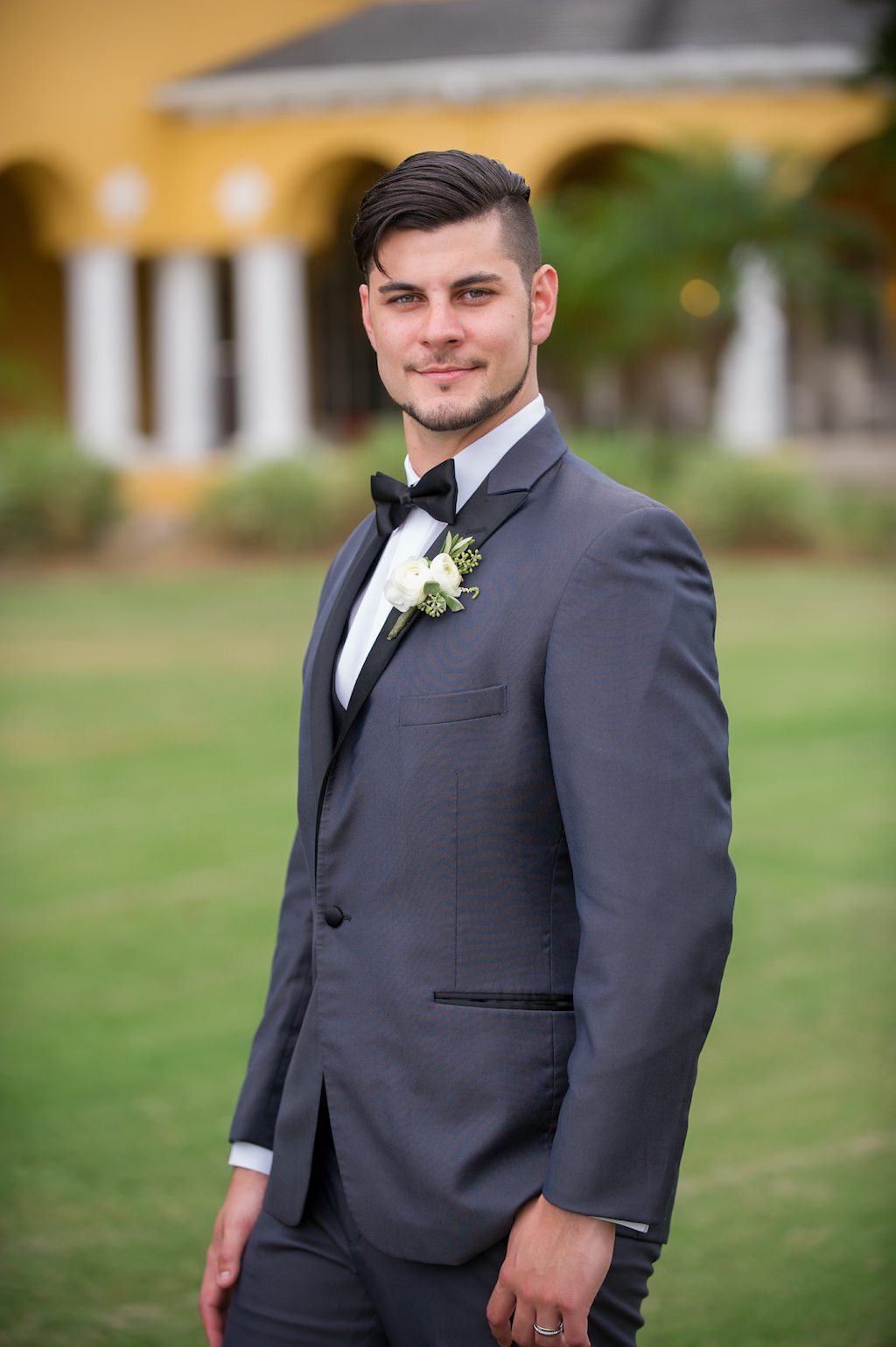Outdoor Garden Groom Portrait wearing Gray Tuxedo with White Rose and Greenery Boutonnière | Tampa Bay Wedding Photographer Andi Diamond Photography