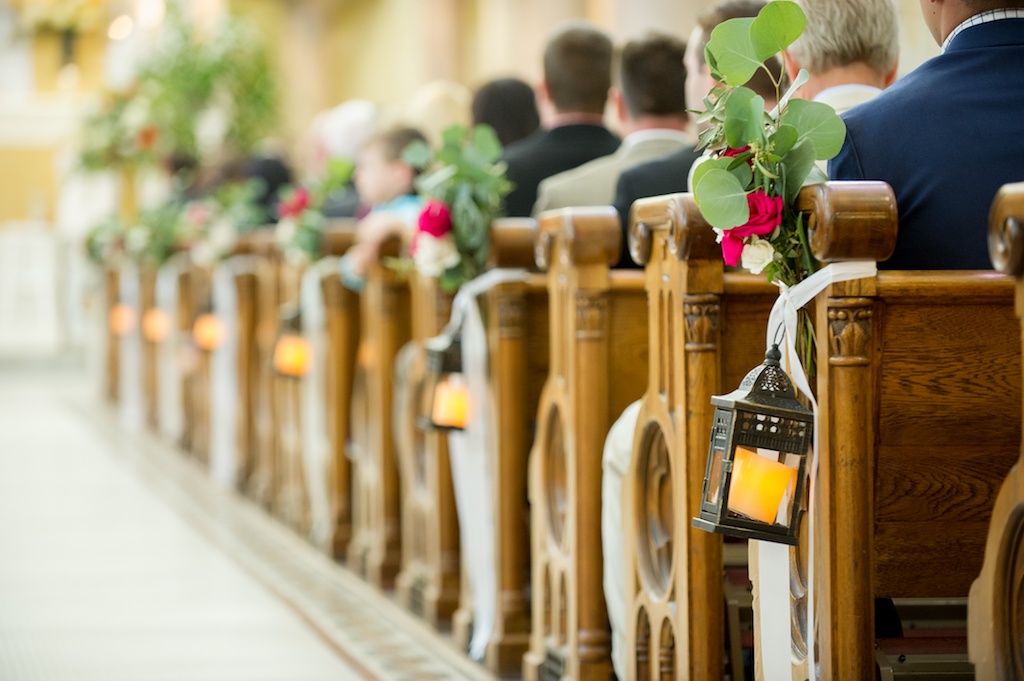 Traditional Church Ceremony Wooden Pew Decor with Magenta Rose and Greenery with White Ribbon Florals and Hanging Antique Lanterns
