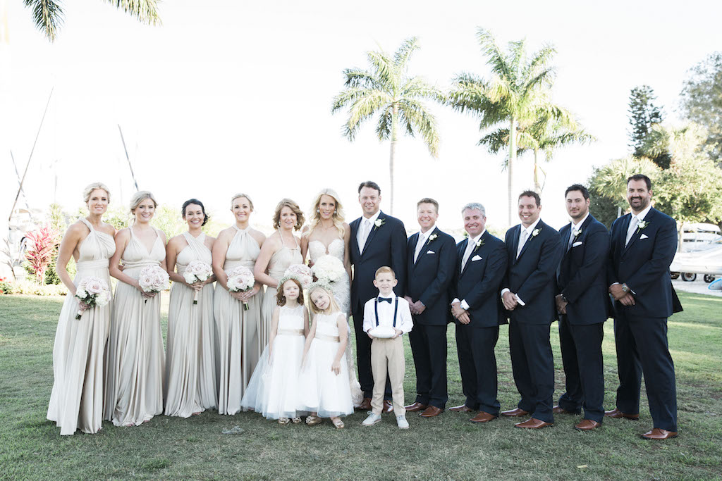 Outdoor Wedding Party Portrait with Bridesmaids in Mismatched Ivory Dresses with BLush and White Rose Bouquets, Grooms in Navy Suits with Gray Ties, Flower Girls in White Belted Dresses and Ring Bearer with Suspenders and Bow Tie | Tampa Bay Wedding Photographer K&K Photography | Sarasota Waterfront Wedding Venue Sarasota Yacht Club