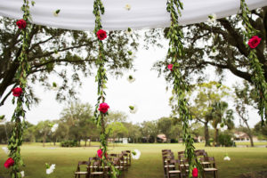Outdoor Wedding Ceremony Decor with Arch with White Drapery and Hanging Greenery Garlands with Red Roses and White Flowers and Wooden Folding Chairs | Clearwater Golf Course Wedding Venue Countryside Country Club | Planner Special Moments Event Planning | Florist & Draping Gabro Event Services