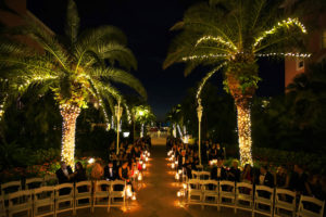 Outdoor Nighttime Courtyard Garden Wedding Ceremony with Folding White Chairs and Floating Votive Candles in Glass Cylinder Vases | St Pete Beach Historic Hotel Wedding Venue The Don Cesar