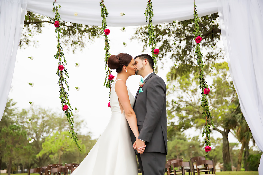 Outdoor Wedding Ceremony Portrait with Arch with White Drapery and Hanging Greenery Garlands with Red Roses and White Flowers and Wooden Folding Chairs | Clearwater Golf Course Wedding Venue Countryside Country Club | Planner Special Moments Event Planning | Florist and Decor Gabro Event Services