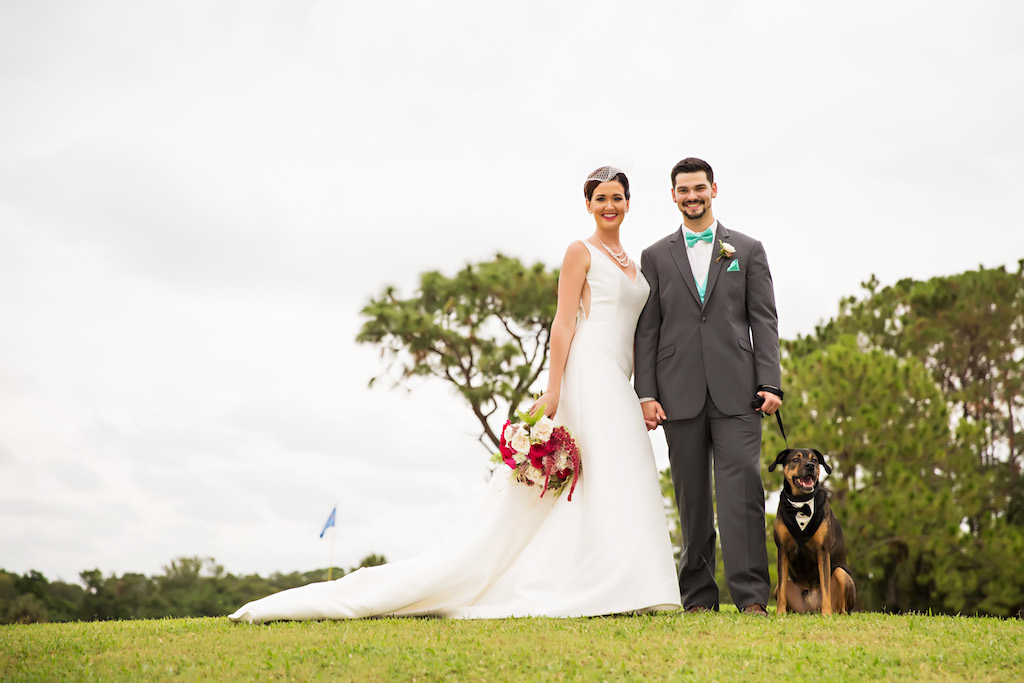Outdoor Garden Wedding Portrait, Bride in Long Train A Line Wedding Dress and Birdcage Veil with Pearl Bridal Jewelry, with White, Magenta, and Fern Bouquet, Groom in Gray Suit with Teal Bow Tie and Pocket Square, and Dog of Honor in Tuxedo | Clearwater, Florida Golf Course Wedding Venue Countryside Country Club | Pet Care Planning Fairy Tale Petcare