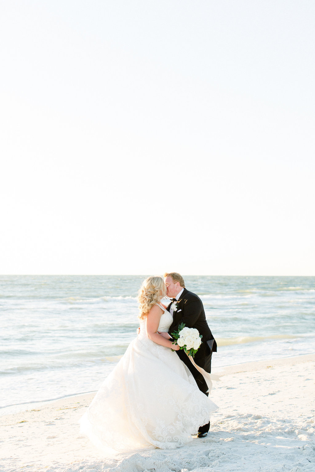 Beach Wedding Bride and Groom Portrait with White Rose and Greenery Bouquet with Long Gold Ribbon, Groom in Black Tuxedo | Tampa Bay Beachfront Wedding Venue The Carlouel Yacht Club | Clearwater Wedding Photographer Ailyn La Torre Photography