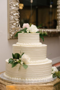 Three Tiered Round White Wedding Cake with Blush Roses and Greenery on Gold Octagonal Cake Stand