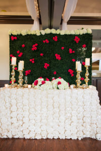 Ballroom Wedding Reception Sweetheart Table with Textured White Rose Floral Linen, Low White Hydrangea and Red Rose Centerpiece, and Bold Stylish Gold Candlesticks, and Greenery and Red Rose Floral Wall Backdrop | Tampa Bay Wedding Planner Special Moments Event Planning | Clearwater Wedding Florist and Rentals Gabro Event Services