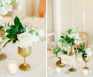 Old Florida Inspired Wedding Reception Table Decor with Small White Floral with Greenery Centerpieces in Mismatched Antique Gold Vases and Elegant Green on White Lettered Table Number Card | Tampa Bay Wedding Planner Glitz Events