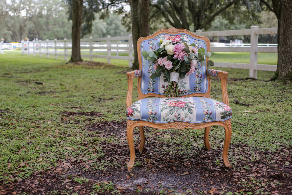 Pink and Ivory Roses with Greenery and White Ribbon Bridal Bouquet on Antique Upholstered Chair | Tampa Bay Farm Wedding Venue Lange Farm