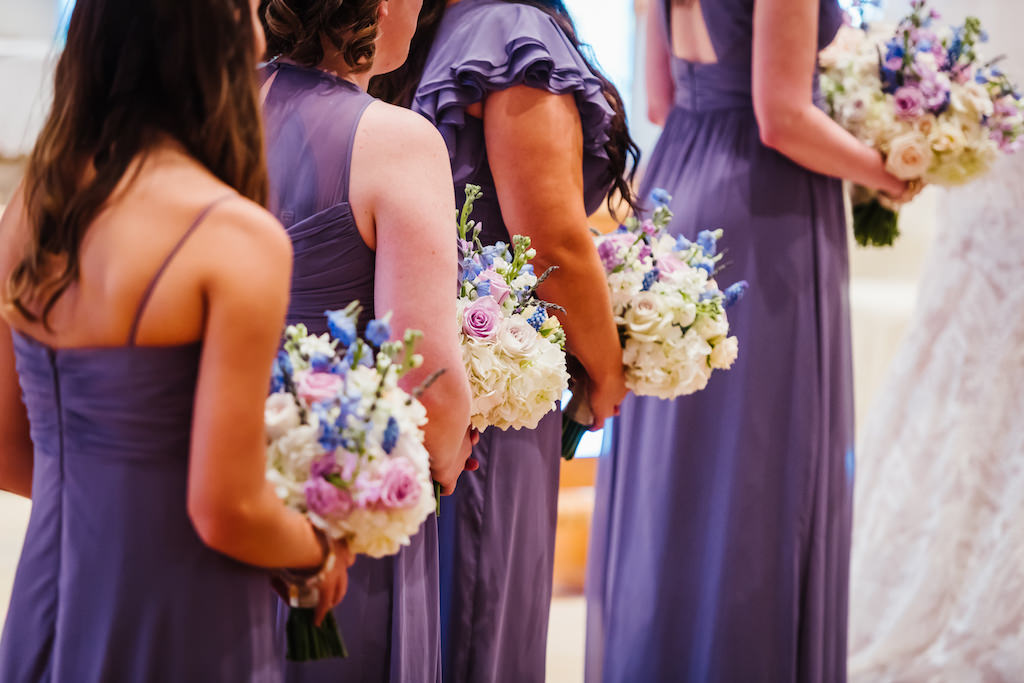 Wedding Ceremony Bridesmaids Portrait wearing Mismatched Dusty Purple Dessy Dresses holding White, Purple Rose, and Blue Floral Bouquets with Greenery