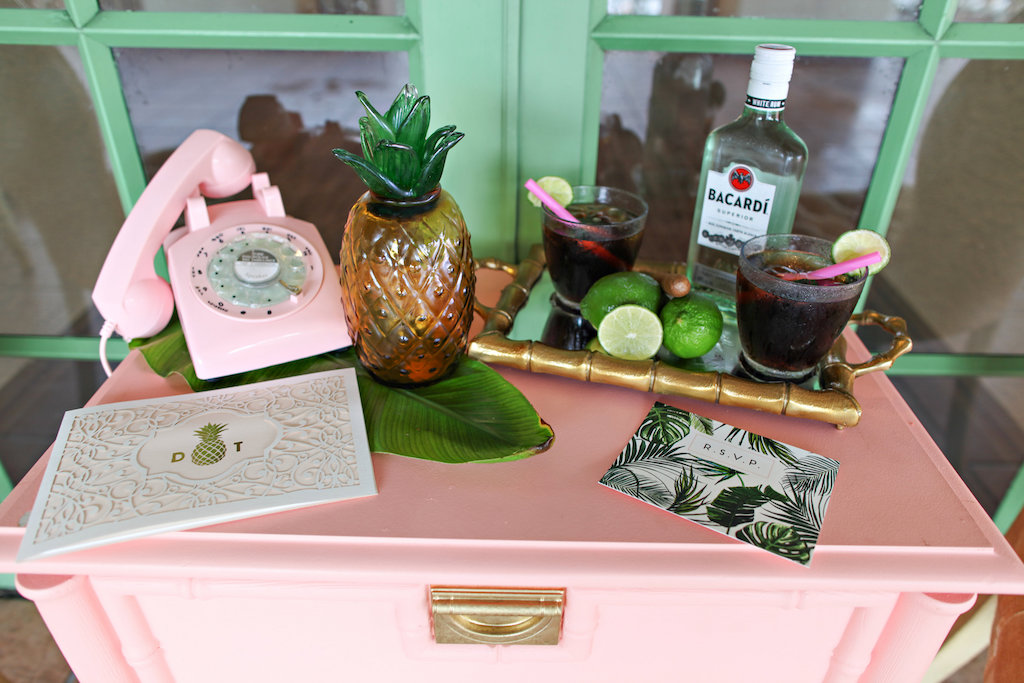 Hotel Courtyard Old World Havana Cuban Inspired Wedding Reception with Pink Table with Rotary Phone, Pineapple Decor and Rum Cocktail Setup, with White and Blush Laser-cut Gold Pineapple Invitation, and Palm Frond Green and White RSVP Card | Vintage Rentals by St. Pete A Chair Affair