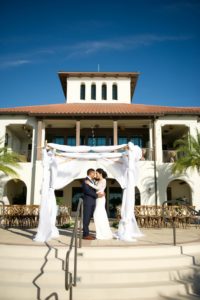 Outdoor Waterside Wedding Ceremony Portrait, Bride and Groom Under White Draped Ceremony Arch | Tampa Bay Waterfront Wedding Ceremony Venue Westshore Yacht Club