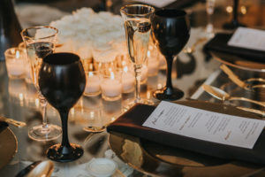Sophisticated Black, White, and Gold Wedding Reception Table Decor with Gold and White Printed Menu, Gold Charger and Flatware, Black Linen and Black Wine Glasses | Tampa Bay Wedding Papergoods URBANcoast | Linen Rentals Over the Top Linen Rentals | Wedding Planning UNIQUE Weddings and Events