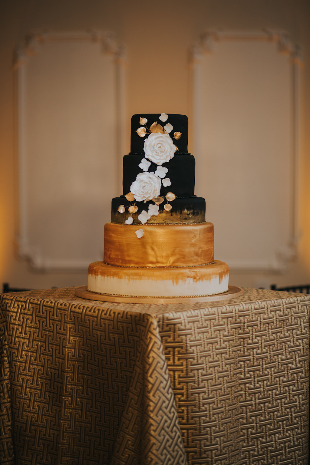 Sophisticated Black, White and Gold Five Tier Round Wedding Cake with Black to Gold Ombre and White and Gold Florals on Gold Cake Stand on Geometric Gold Linen | Tampa Bay Wedding Cake Bakery Alessi Bakery | Linen Rental Over The Top Linen Rentals