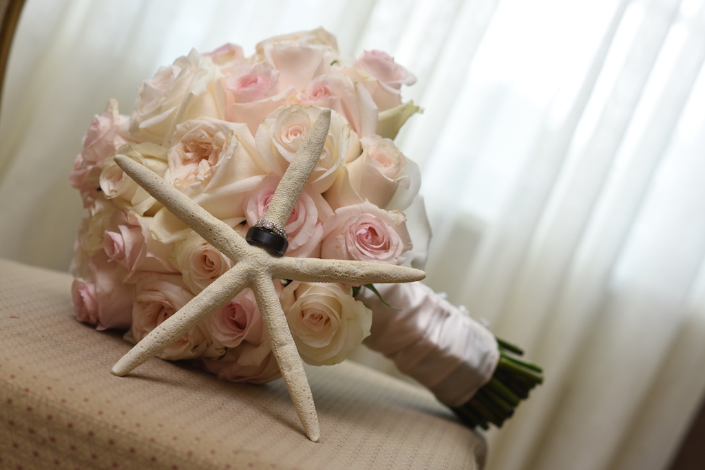 Blush Pink and Cream Rose Bouquet with White Ribbon and Groom's Black Wedding Band and Diamond Wedding Ring on Starfish