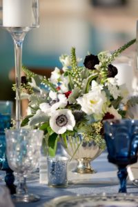 French Countryside Inspired Wedding Reception Table Decor with Low Anemone, Dark Red and Burgundy and White Flower Centerpiece with Greenery in Antique Silver Bowl Vase, with Blue Colored Drinking Glasses | Tampa Wedding Planner Kelly Kennedy Weddings and Events