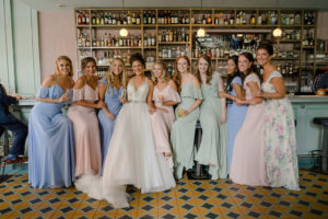 Interior Bridal Party Portrait at Bar, Bride in Jeweled Halter Ballgown Madeline Gardner Wedding Dress, Bridesmaids in Mismatched Blue, Pink, and Green Morilee Bridal Floorlength Dresses | Tampa Bay Wedding Photographer Marc Edwards Photography | South Tampa On Swann