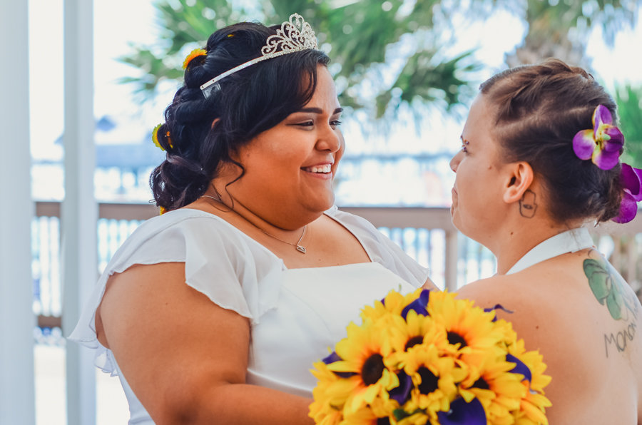 Outdoor Same Sex Wedding Bridal Ceremony Portrait with Purple Orchid Hair and Princess Tiara Hair Accessories, and Sunflower and Purple Calla Lily Bouquet | Purple and Yellow Disney Inspired Tampa Bay Wedding