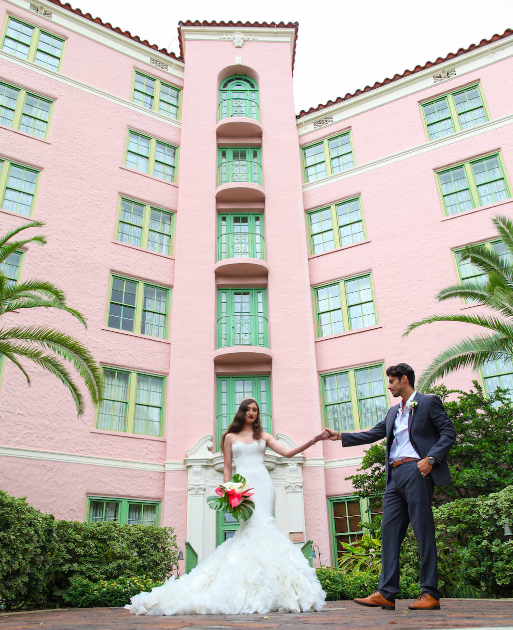 Outdoor Hotel Garden Wedding Portrait, Bride in Layered Mermaid Ines Di Santo Strapless Wedding Dress with Pink and White Lily with Green Fern Tropical Bouquet, Groom in Gray Suite with Boutonniere | St Petersburg FL Historic Venue Vinoy Renaissance