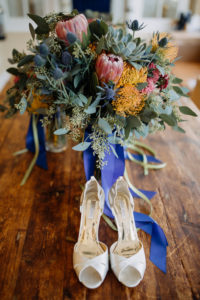 Orange, Red, and Sage Greenery and Succulent Bridal Bouquet with Blue and Green Ribbon and Peep Toe Laura Porto Wedding Shoes