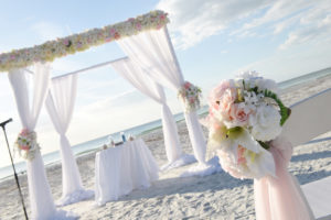 Outdoor Pink and White Beach Wedding Ceremony with White Drapery and Wedding Arch with Pink and White Roses and Tropical Flowers | St Pete Beach Wedding Venue The Don Cesar