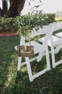 Outdoor Garden Wedding Ceremony White Folding Chair with Wooden Painted Reserved Sign with Greenery Florals and Sage Green and Cobalt Blue Ribbon
