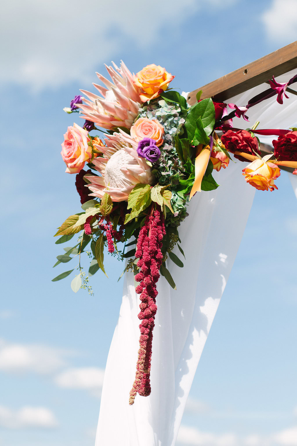 Whimsical Jewel Tone Blush Pink, Magenta, Red, Orange and Purple Tropical Wedding Ceremony Arch Flowers with White Draping