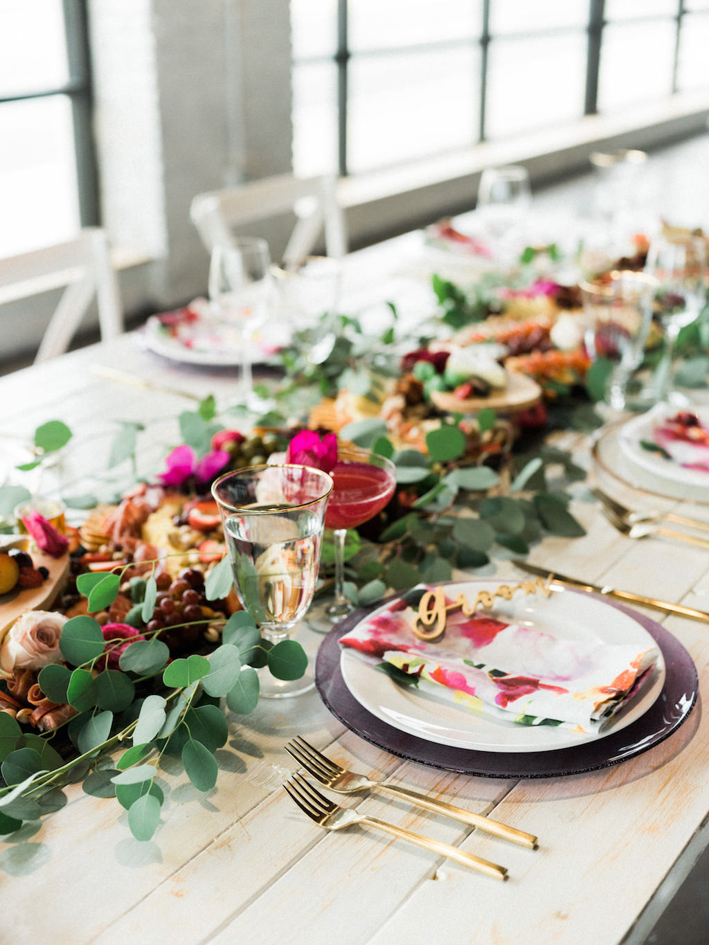 Modern Fuchsia Wedding Reception Table with Charcuterie Board with Greenery, Wooden Table, White Cross Back Chairs, Gold Flatware | Lakeland Florida Wedding Caterer Tastes of Tampa Bay | Chair Rentals A Chair Affair | Venue Haus 820