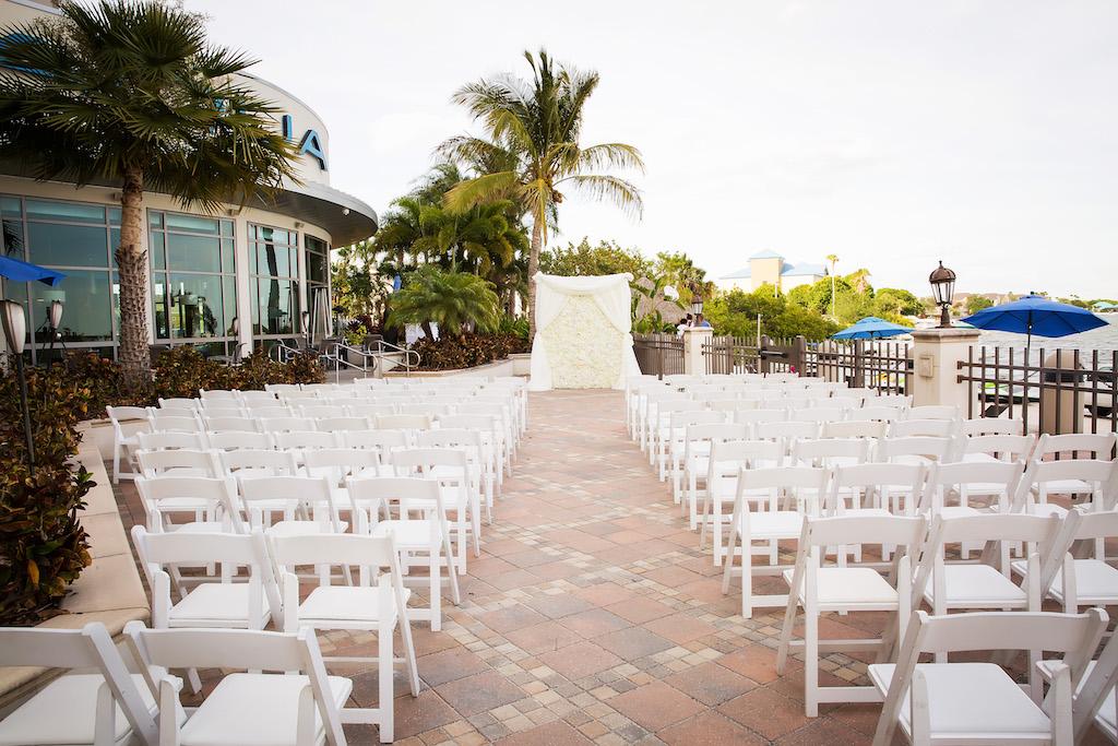 Hotel Courtyard Wedding Ceremony with Folding White Chairs and White Draped Rose Floral Ceremony Backdrop | Waterfront Wedding Venue The Westin Tampa Bay
