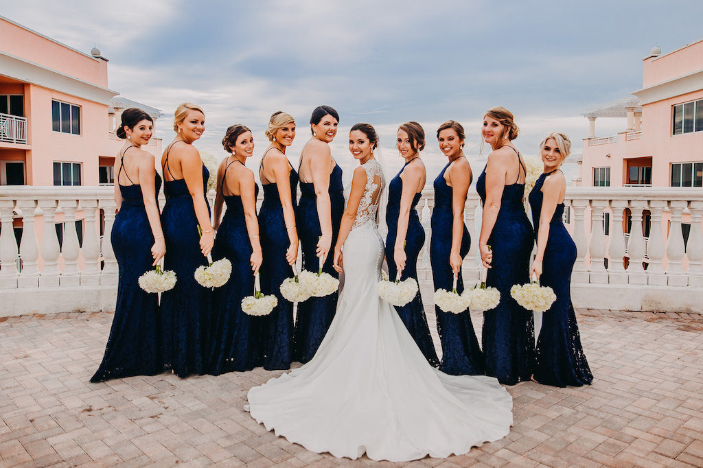 Outdoor Rooftop Bridal Party Portrait, Bridesmaids in Halter Navy Blue Column Lulu's Zenith Dresses, Bride in Lace Cap Sleeve A Line Sincerity Bridal Wedding Dress, with White Floral Bouquet | Tampa Bay Wedding Photography Rad Red Creative | Waterfront Hotel Wedding Venue Hyatt Regency Clearwater Beach