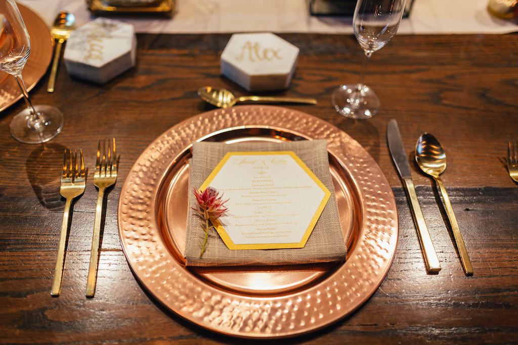 Organic Geometric Wedding Reception Table Setting with Copper Charger, Gold Flatware, Hexagonal Gold and White Printed Menu and Marble Place Card with Gold Script, on Wooden Table | Tampa Wedding Planner UNIQUE Weddings and Events