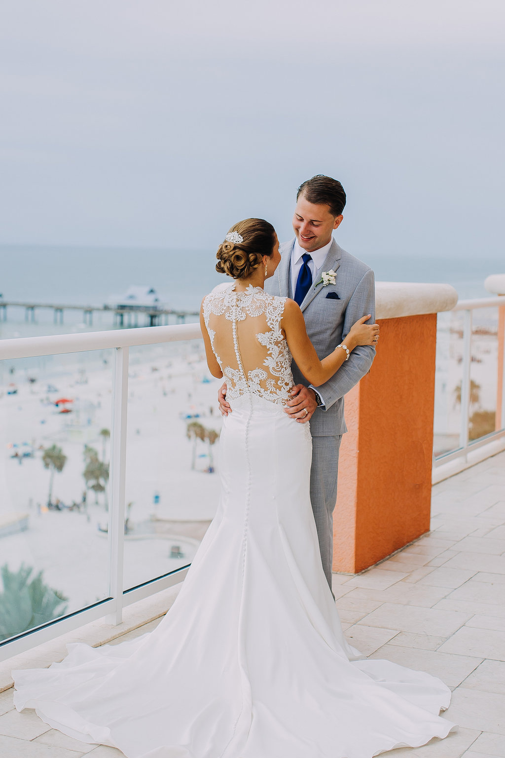 Outdoor Rooftop Bride and Groom Wedding Portrait, Bride in Lace Illusion Back Sincerity Bridal Wedding Dress, Groom in Gray Suit with Navy Blue Tie and White Floral Boutonniere | Tampa Bay Beachfront Hotel Wedding Venue Hyatt Regency Clearwater Beach | Wedding Photographer Rad Red Creative