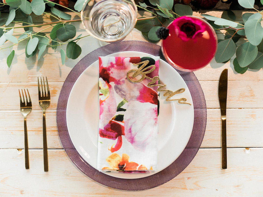 Modern Fuchsia Wedding Reception Table Setting with Watercolor Printed Napkin, Gold Flatware, Glass Charger, Gold Bride Die Cut Place Card | Lakeland Wedding Dish and Charger Rentals A Chair Affair