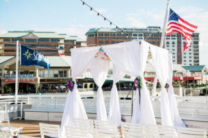 Outdoor Waterfront Wedding Ceremony with White Folding Chairs, White Draped Chuppah Wedding Arch with Purple, Blue, White, and Red Flowers | Tampa Bay Nautical Wedding Venue Yacht StarShip