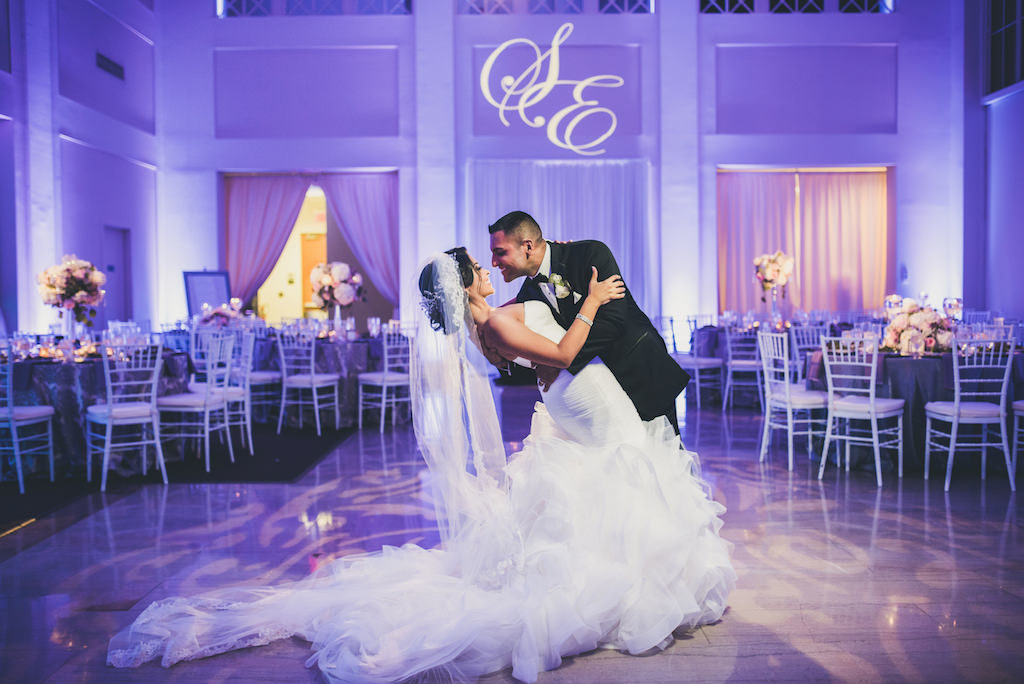 Modern Violet Wedding Reception Bride and Groom First Dance Portrait, Bride in Layered Mermaid Strapless Pronovias Dress, with White Chiavari Chairs and White and Pink Tall Centerpieces | Downtown Tampa Wedding Venue The Vault | Planner Special Moments Event Planning | Custom Monogram Projection and Purple Uplighting Nature Coast Entertainment | Tampa Bay Wedding Shop Isabel O'Neil Bridal Collection