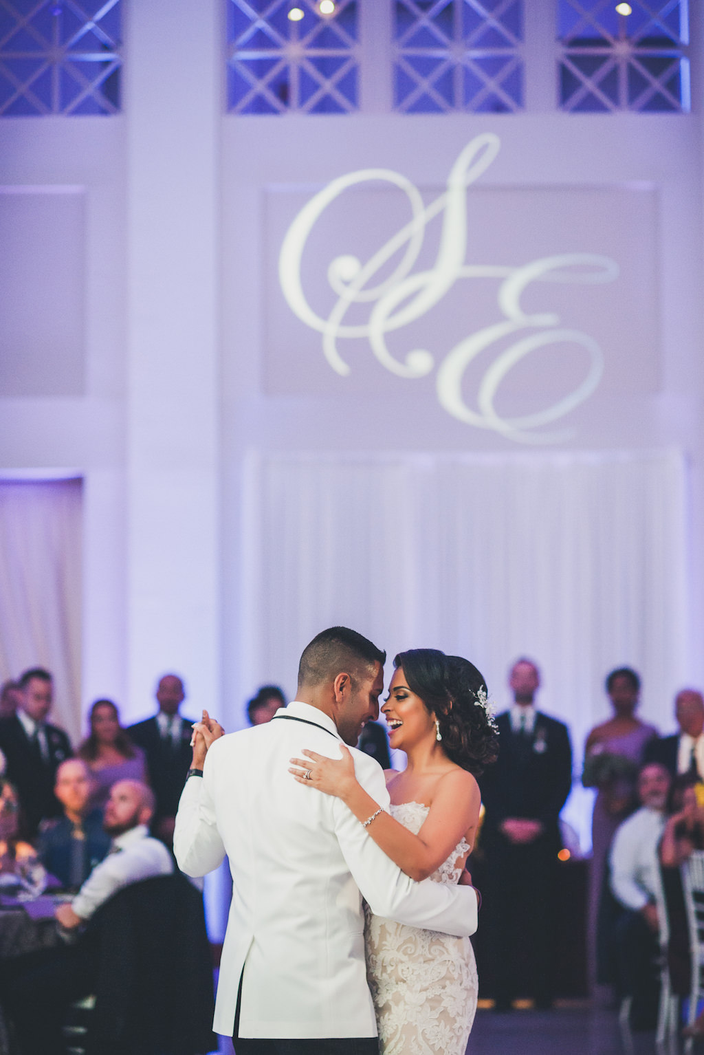 Modern Violet Wedding Reception First Dance Portrait, Groom in White Jacket, Bride in Strapless Ivory Lace Ines Di Santo Dress | Downtown Tampa Wedding Venue The Vault | Custom Monogram Projection and Purple Uplighting Nature Coast Entertainment | Dress Shop Isabel O'Neil Bridal Collection