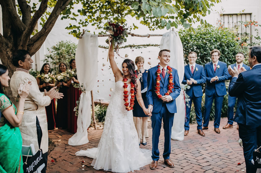 Outdoor Garden Modern Indian Wedding Ceremony Portrait Decor with Hanging Blush, Red, and Orange Rose Garland and White Draped Arch, Groom and Groomsmen in Blue Suits, Bridesmaids in Red Dresses | Tampa Bay Wedding Venue St Petersburg Museum of Fine Arts | Wedding Photography Rad Red Creative | Menswear Sacino's Formalwear