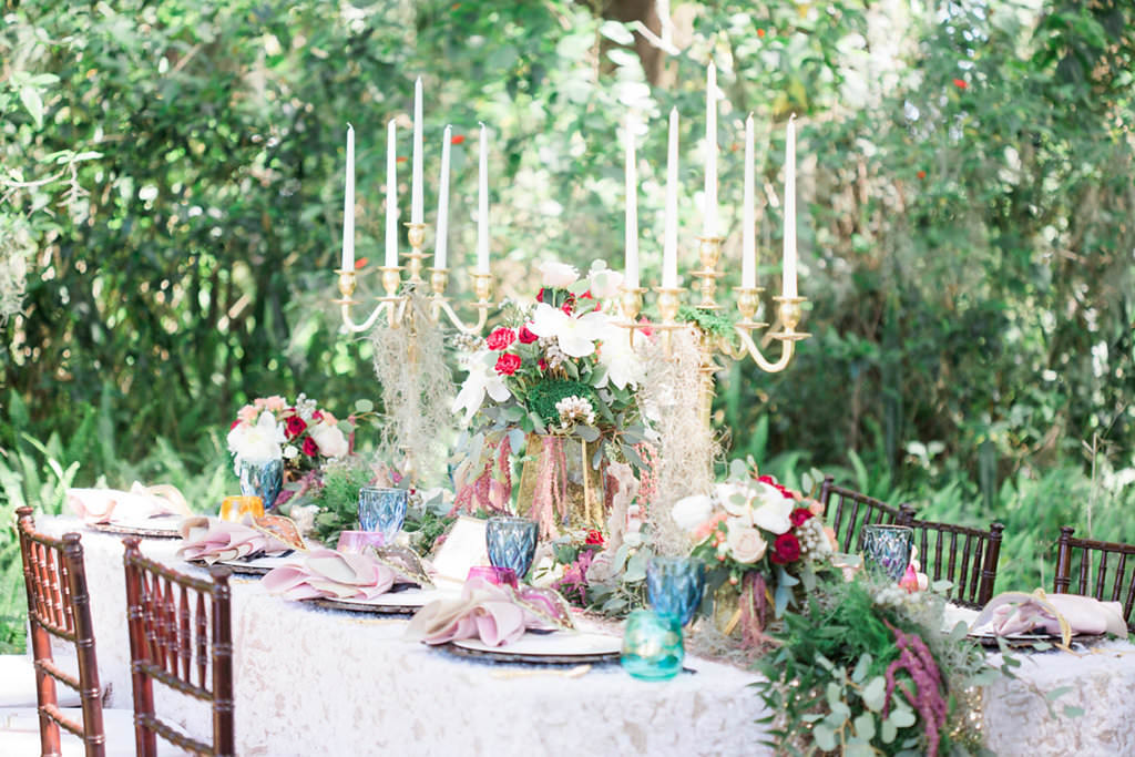 Outdoor Whimsical Boho Garden Wedding Reception Decor with Vintage Mismatched Dishes and Garland Floral Table Runner and Candelabra Centerpiece | Over the Top Rental Linens