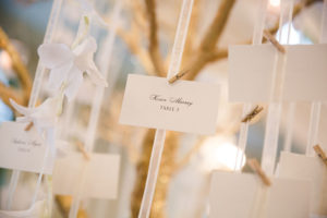 White and Gold Wedding Reception Escort Cards with Mini Clothes Pins on White Ribbon with Hanging White Orchids on Gold Branch