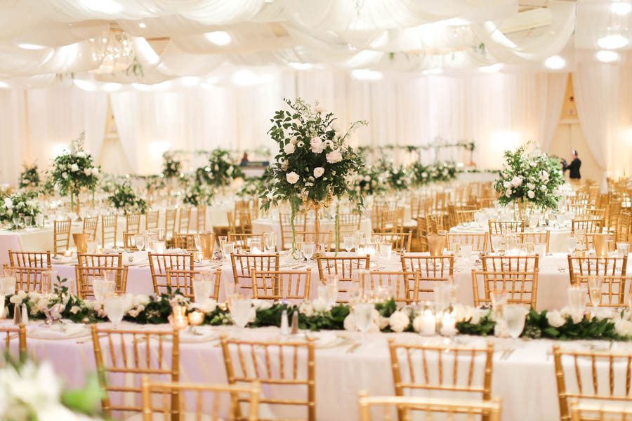 White and Greenery Ballroom Wedding Reception with Long Feasting Tables, Tall White Floral and Greenery Centerpiece in Gold Candelabra, and Long Garland Centerpiece, with Gold Chiavari Chairs | White Ceiling Draping by Tampa Bay Gabro Event Services | Tarpon Springs Wedding Venue Inverness Hall at Innisbrook Resort