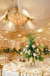 White and Greenery Ballroom Wedding Reception with Tall White Floral and Greenery Centerpiece in Gold Vase with Gold Chiavari Chairs | White Ceiling Draping by Tampa Bay Gabro Event Services | Tarpon Springs Wedding Venue Inverness Hall at Innisbrook Resort
