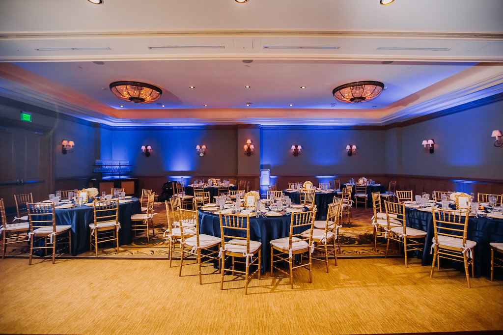 Hotel Ballroom Navy Blue and Gold Reception with Blue Linens, Gold Chiavari Chairs with White Cushions, and Blue Uplighting | Tampa Bay Wedding Lighting and Rentals Gabro Event Services | Hotel Wedding Venue Hyatt Regency Clearwater Beach