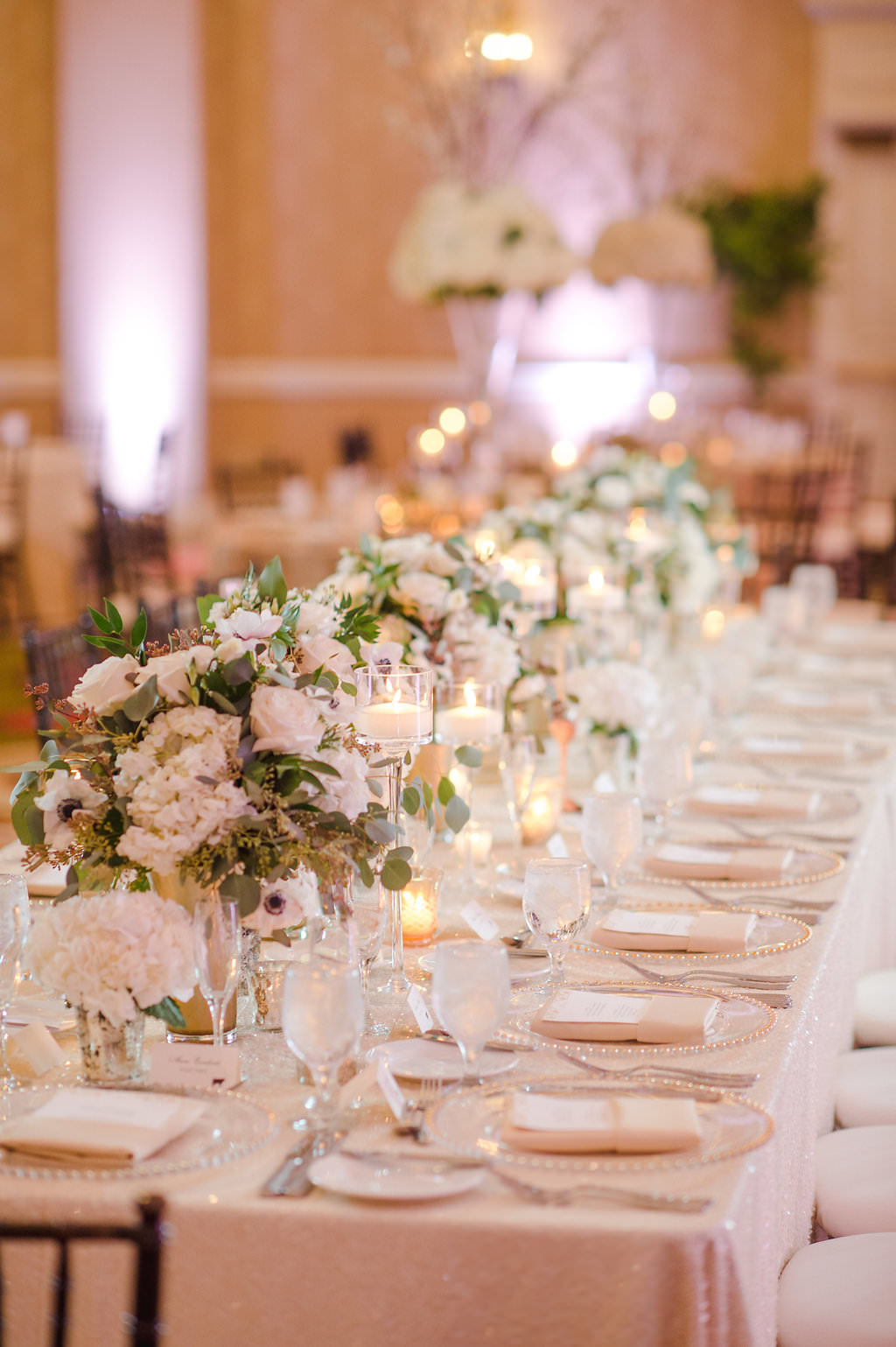 Hotel Ballroom Gold and White Wedding Reception Long Feasting Table with Black Chiavari Chairs, Low white and Greenery centerpieces in Gold Vases with votive candles and white draping | Tampa Bay Historic Wedding Venue The Vinoy