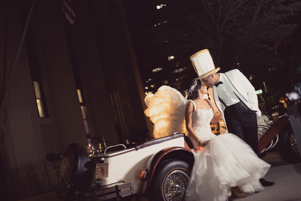 Outdoor Nighttime Bride and Groom Portrait, Bride in Lace Layered Mermaid Ines Di Santo Dress, Groom in White Tuxedo with Hora Loca Props Angel Wing and Oversized Top Hat with Classic Antique Car | Tampa Bay Wedding Planner Special Moments Event Planning | Dress Shop Isabel O'Neil Bridal