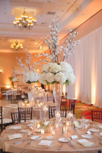 Hotel Ballroom Gold and White Wedding Reception Round Table Decor with Tall White Hydrangea, Pussy Willow Branches and Greenery Centerpiece in Clear Glass Vase with votive candles and blush linens | St Pete Historic Wedding Venue The Vinoy