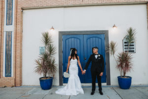 Outdoor Downtown Tampa Modern Indian Wedding Bride and Groom Portrait, Bride in Strapless Mermaid Wedding Dress, Groom in Black Tuxedo with White Rose Boutonniere | Wedding Photographer Grind and Press Photography