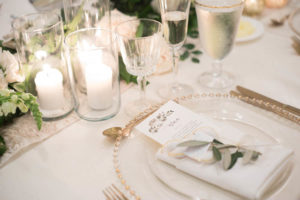 White and Greenery Wedding Reception Table Setting with Gold Beaded Glass Charger, White Linens, Pillar Candles in Glass Cylinders | Tampa Bay Flatware and Glass Rentals A Chair Affair